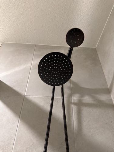 Customer's oil rubbed bronze dual shower head set installed in a tiled shower, viewed from a low angle.