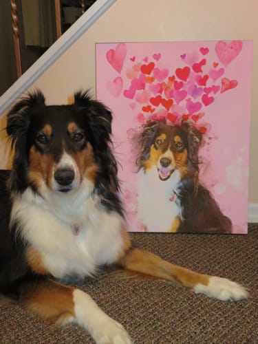 Customer's dog posing next to its Custom Pet Portrait showing the dog on a pink background with watercolor hearts.
