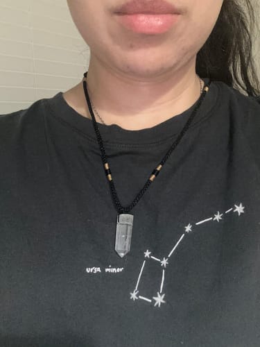 Reviewer wearing a clear quartz necklace from the VIP Crystal Club against a dark shirt.