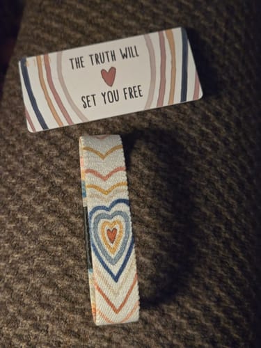 Reviewer's 'The Truth Will Set You Free' Bible Verse Bracelet with a colorful heart pattern, shown next to its matching card.