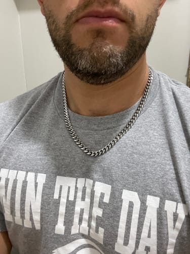 Primer plano de un cliente usando la Cadena Cuban Link plateada sobre una camiseta gris.