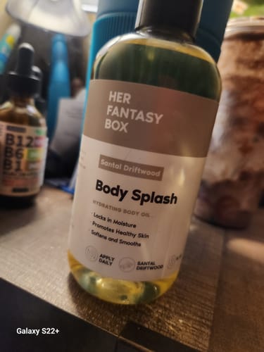 Customer's Santal Driftwood Body Splash bottle, a hydrating body oil, shown on a counter.