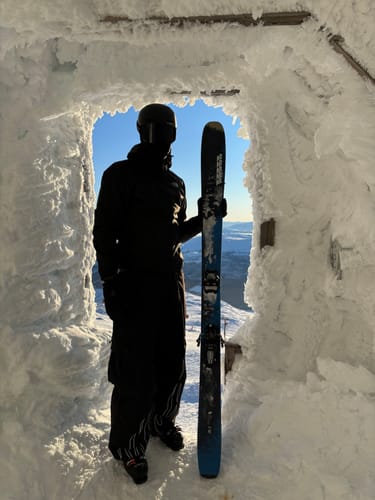 Reviewer wearing the baggy utility snow pants with visible flame cuffs, standing silhouetted in a snowy archway.