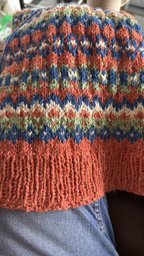 Close-up of a reviewer's colorful project from the January Mystery Knitting Box, showing an intricate pattern and ribbed cuff.