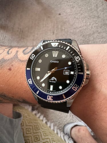 Primer plano del reloj Casio Marlin Duro 'Batman' en la muñeca de un cliente, mostrando su bisel negro y azul.