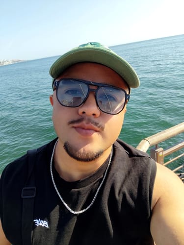 Cliente luciendo la Cadena Snake plateada sobre una camiseta sin mangas negra, con el mar de fondo.