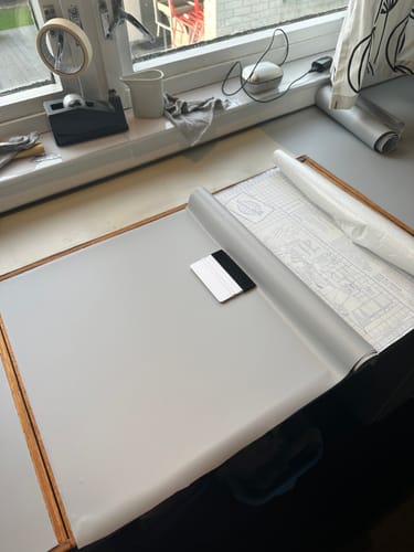 Kunde i ferd med å legge Premium Cloudy grey kontaktplast på en bordplate med nal.