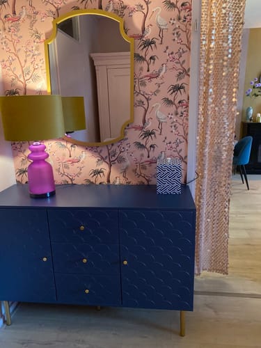 Klant's Mauro Ferretti Milva Tafellamp met een roze voet en groene kap, verlicht op een blauw dressoir.