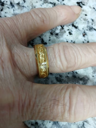 Close-up of a customer's hand wearing the gold Aureum ring, showing the textured foil inlay.