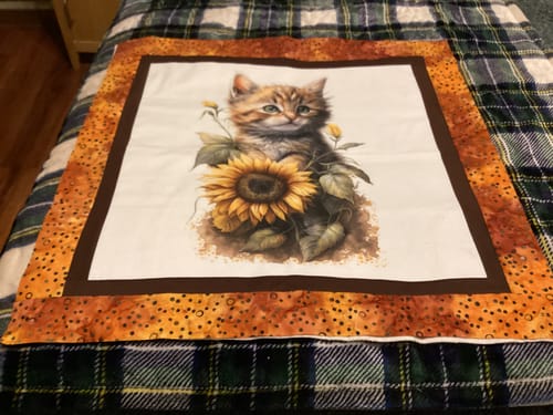 Reviewer's Sunflowers & Kittens fabric panel sewn into a quilt with a brown inner and patterned orange outer border.