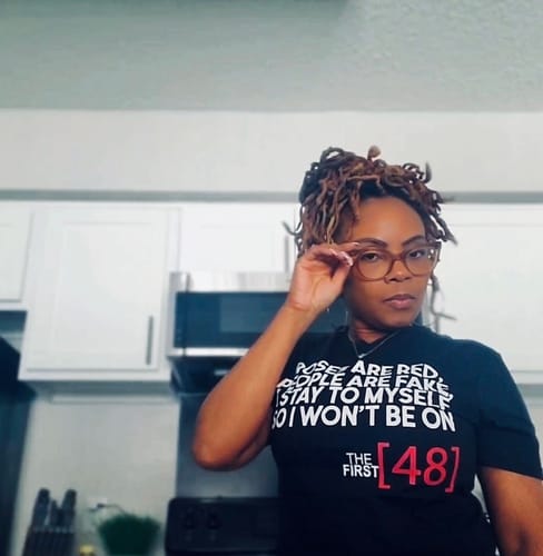 Reviewer posing in a kitchen while wearing the black 'The First 48' t-shirt with a funny saying.