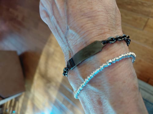 Reviewer wearing the black Anchor Link ID Bracelet on their wrist, stacked with a silver bracelet.