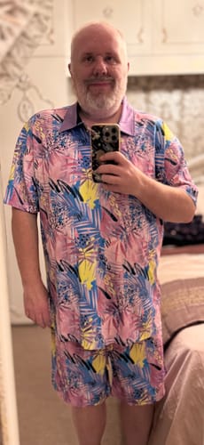 Reviewer in a mirror selfie wearing the colorful 'Plum Lake' All-Day Polo with matching shorts.