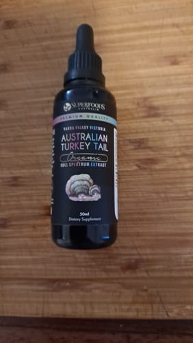 Customer's bottle of Australian Turkey Tail tincture with a black dropper, standing on a wooden surface.