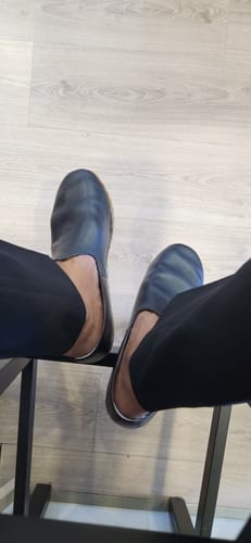 Reviewer wearing the Ahmad Black Leather Yemeni Shoes, showing a top-down view of their feet while seated.