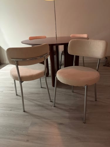 Recensent toont twee beige by fonQ Bent eetkamerstoelen aan een donkere ronde eettafel.