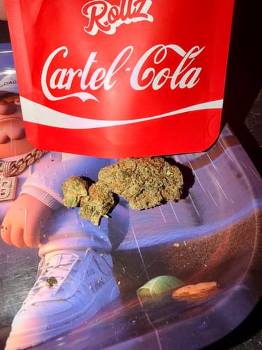 Customer's Cartel Cola THCA Flower buds on a tray in front of the red product pouch.