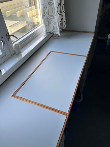 Anmelder viser den ferdiglagte Premium Cloudy grey kontaktplasten på en lang benk ved vinduet.