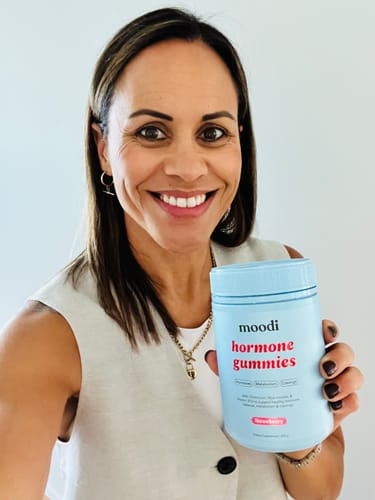 Reviewer smiling while holding a light blue tub of Strawberry Hormone Gummies.