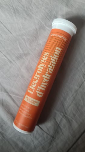 Photo d'un client : le tube orange des Électrolytes d’hydratation sur un tissu gris.