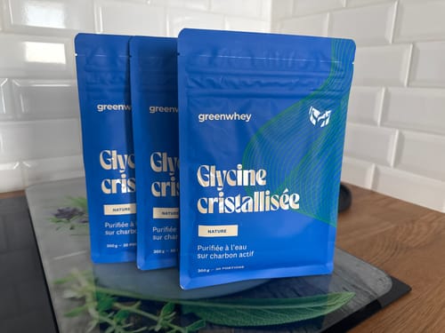 Un client montre trois sachets bleus de Glycine cristallisée sur un comptoir de cuisine.