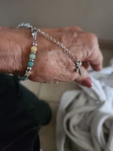 A customer's wrist wearing the beaded Religious Cross Bracelet, showing the adjustable chain and small cross charm.