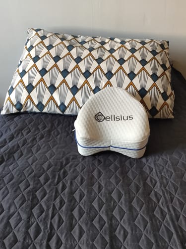Le coussin orthopédique pour genoux Cellsius d'un client, posé sur une couverture de lit grise.