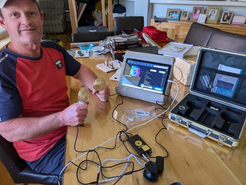 Customer sits at a table with the complete Qi Coil™ 3S System, holding the two coils while viewing the Resonant Console 2.