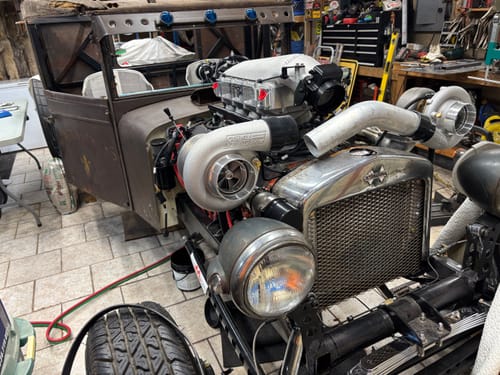 Reviewer's vintage hot rod project in a garage, showcasing a powerful twin-turbo engine setup using the brand's parts.