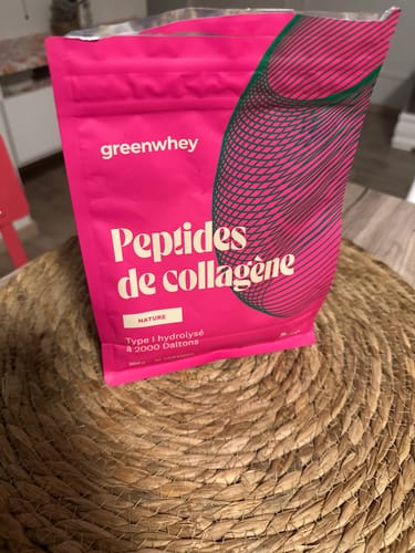 Sachet rose vif des Peptides de Collagène d'un client, posé sur un set de table rond et tressé.