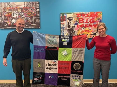 Two customers holding their large Premium T-Shirt Quilt made from a collection of NAMI Walks t-shirts.