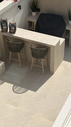 Reviewer's two Jumbo Indoor/Outdoor Barstools with woven seats at a modern patio bar.