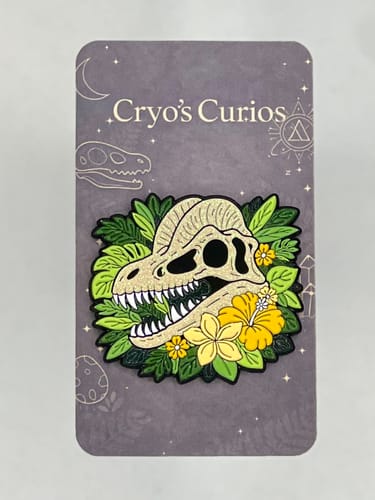 Customer's beautiful custom enamel pin of a crested dinosaur skull with yellow flowers, on its backing card.