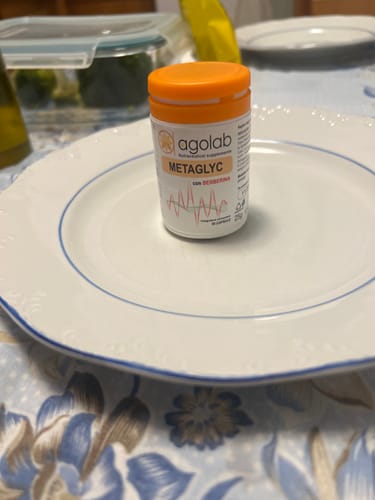 Un cliente mostra il flacone di Metaglyc con un tappo arancione, posizionato al centro di un piatto bianco.