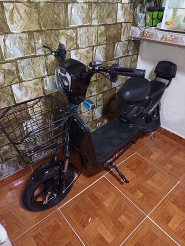 Cliente muestra su bicicleta eléctrica negra Kiwo GY801, que se ve grande y bonita, estacionada en una habitación.