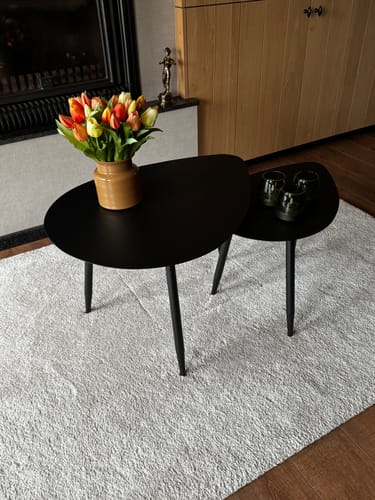 Recensent toont de set van 2 zwarte, druppelvormige bijzettafels in een woonkamer.