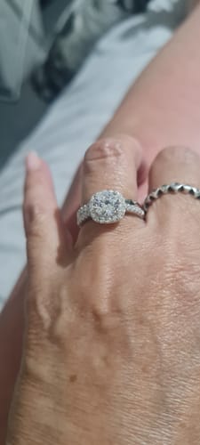 Customer's hand wearing the sparkling silver Aureline wedding set with a halo design.