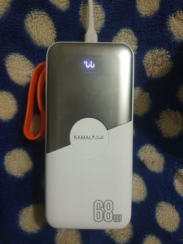 Reviewer's white and silver PD 68W power bank on a patterned surface, showing a faulty digital display.