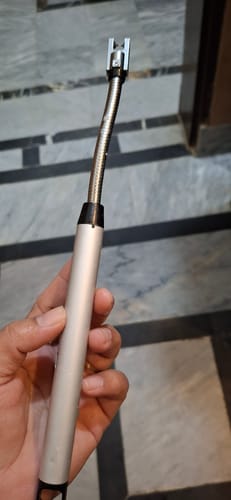 A reviewer holding the flexible rechargeable electric lighter, showing its silver handle and bendable neck.