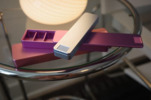 Reviewer's colorful Weekly Case pill organizers on a glass table, with one open showing the interior.
