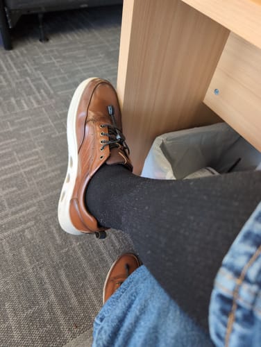 Customer's leg shown wearing the black Performance Compression Socks with a brown shoe.