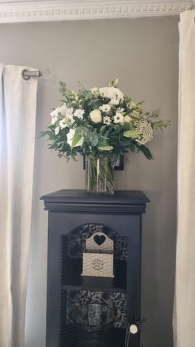 Customer's stunning White Purity Vase Arrangement displayed on a dark cabinet in their home.