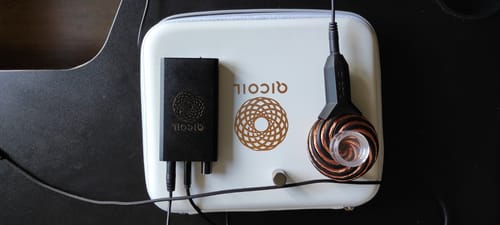 Customer's unboxed Qi Coil™ Mini System, showing the copper coil and black power kit on the white carrying case.
