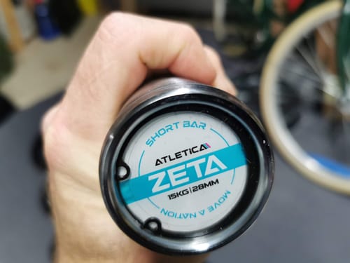 Nahaufnahme der Endkappe der Zeta Langhantel, die von der Hand eines Kunden gehalten wird.