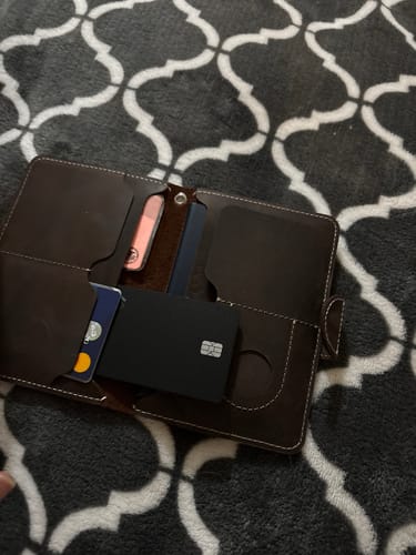 Customer showing the black SPOTMINDERS. Tracking Card PRO placed inside an open brown wallet.
