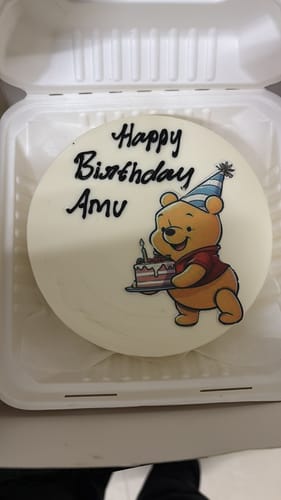 Customer's Winnie the Pooh cake in a box, with a Pooh graphic and 'Happy Birthday Amu' in icing.