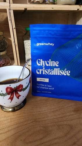 Sachet bleu de Glycine cristallisée d'un client, posé sur une table en bois à côté d'une tasse.