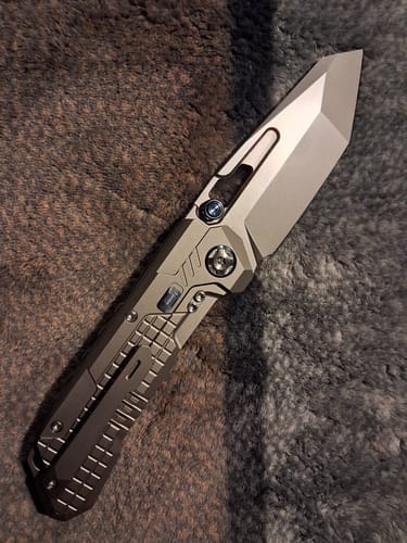 Customer's fully opened Remette RT Cool Leopard knife, showing the thick blade and titanium handle with blue accents on a gray surface.