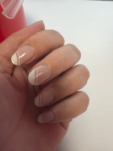Reviewer's hand showing short, rounded nails with Sugar Petal gels, featuring a delicate white swirl design on a sheer base.