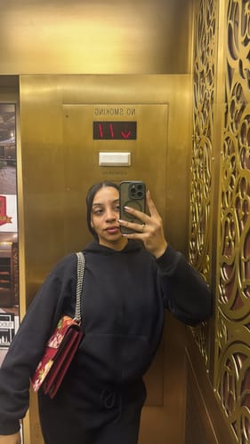 Customer taking a selfie in an elevator, with the Naked Scoop Stirrup Jumpsuit mostly covered by a hoodie.